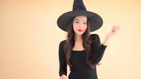 happy pretty asian woman posing to camera in black dress and witch magician hat