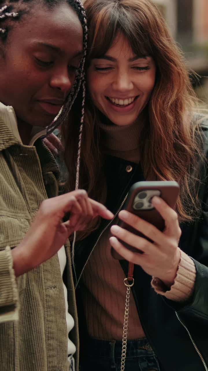 Two Happy Young Women Smiling While Looking at a Smartphone