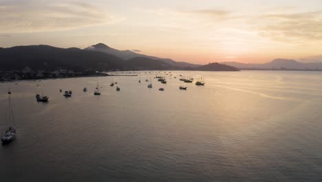 Drone-going-up-revealing-the-sunset-scenery-in-the-ocean-over-the-mountains