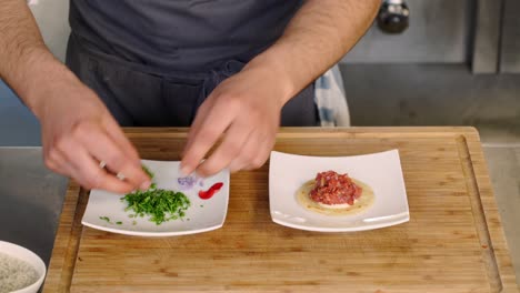 A-chef-adds-garnish-to-an-appetizer-on-a-plate