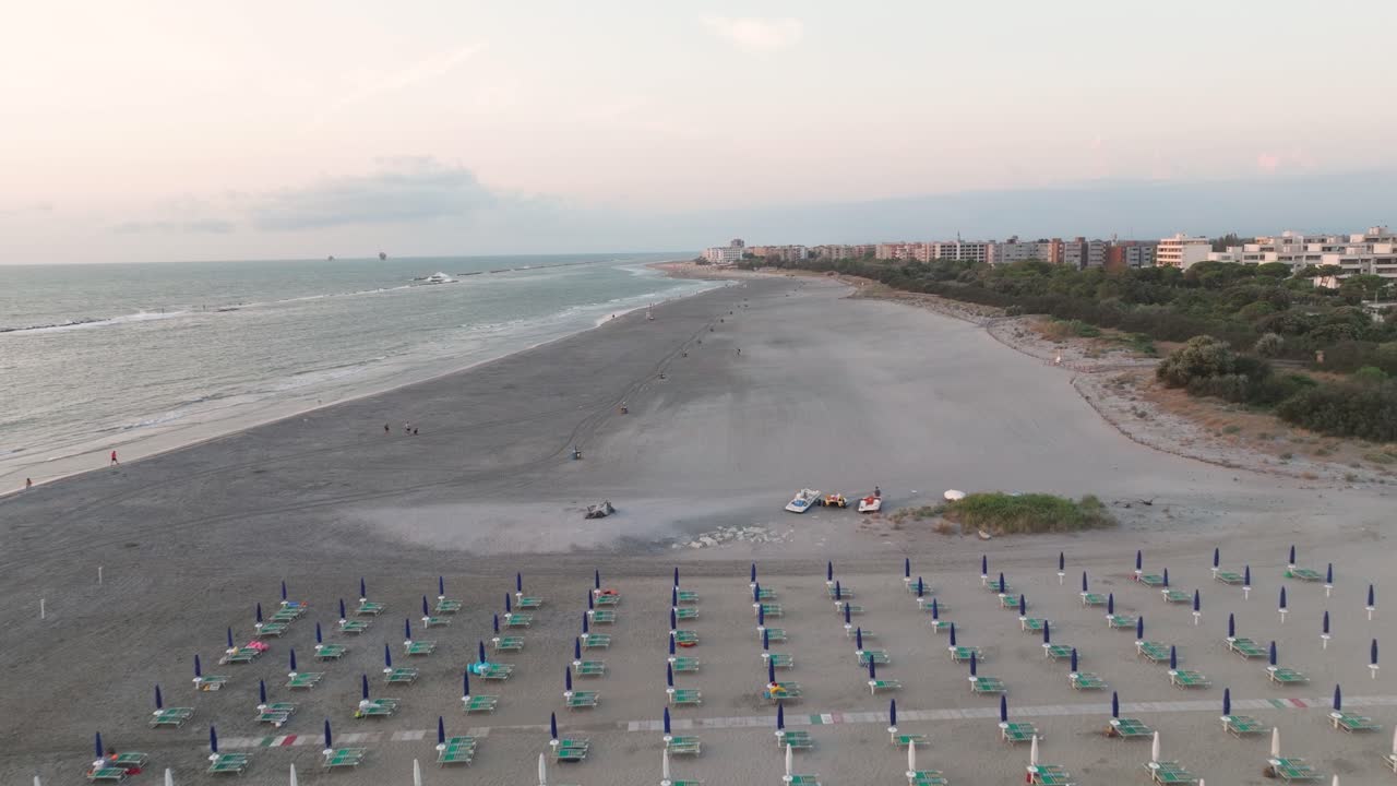 vista aérea de la playa de arena y cerca de la playa de sombrillas al amanecer, típica playa adriática italiana
