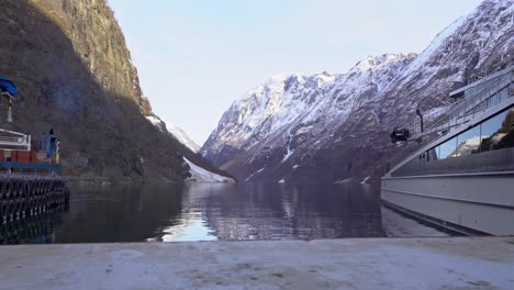 Naeroyfjorden,-Catalogado-Por-La-Unesco,-Visto-Desde-El-Puerto-De-Gudvangen-Con-Un-Barco-Turístico-Eléctrico-Con-Visión-De-Los-Fiordos-A-La-Derecha---Deslizador-De-Movimiento-Lento-De-Derecha-A-Izquierda-Durante-La-Mañana-De-Invierno---Noruega