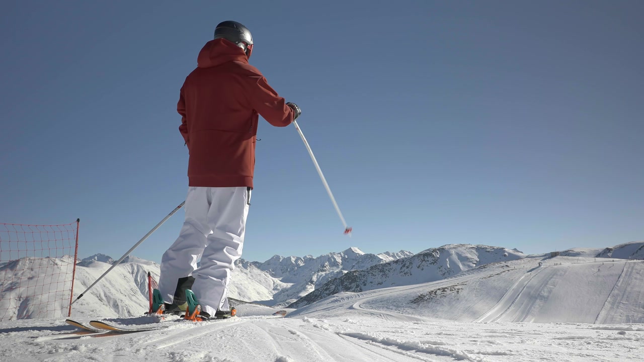 Back View of Skier on Top of Hill Looking Down Ski Piste on Sunny Winter Day