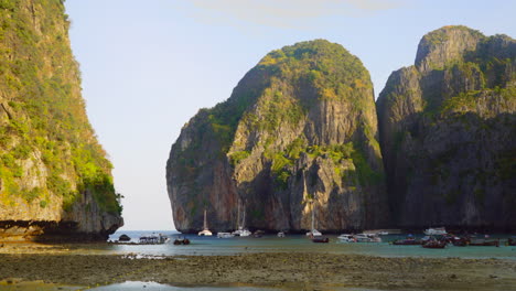 Maya-Bay-ocean-low-tide-sunrise-timelapse-Koh-Phi-Phi-Islands-Phuket-Thailand-long-tail-sailboats-ferry-morning-cruise-near-viking-cave-monkeys-mostly-empty-beach-wind-moving-boats-yellow-golden-sun