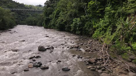 Low-flying-4k-aerial-footage-of-a-brown-river-flowing-within-by-jungle-dominated-riverbanks