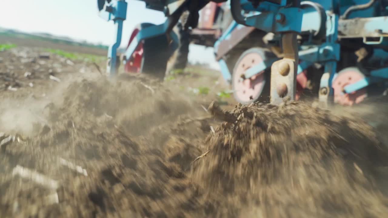 Slow Motion CLOSE UP  tracking shot: A close-up of a part of an agricultural machine is Notched in the ground cultivator. Handles the ground to remove weeds and prevent the drying of the soil