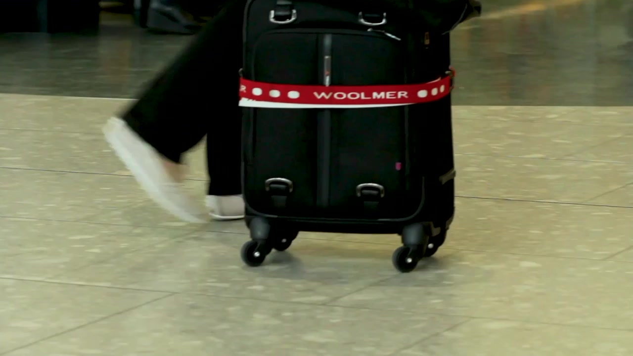 Pies de persona caminando en el aeropuerto con carrito de equipaje