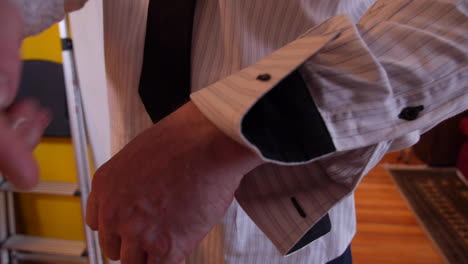 Man-Puts-Cufflinks-Onto-Striped-Shirt,-Gets-Ready-for-Dinner