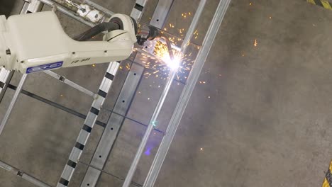 Top-down-aerial-footage-of-a-robotic-welder-welding-joints-together-on-a-steel-frame
