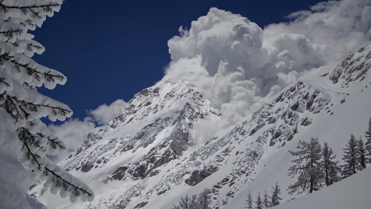 Dramatic video of a snow-covered mountain peak with a low-angle view, capturing towering clouds