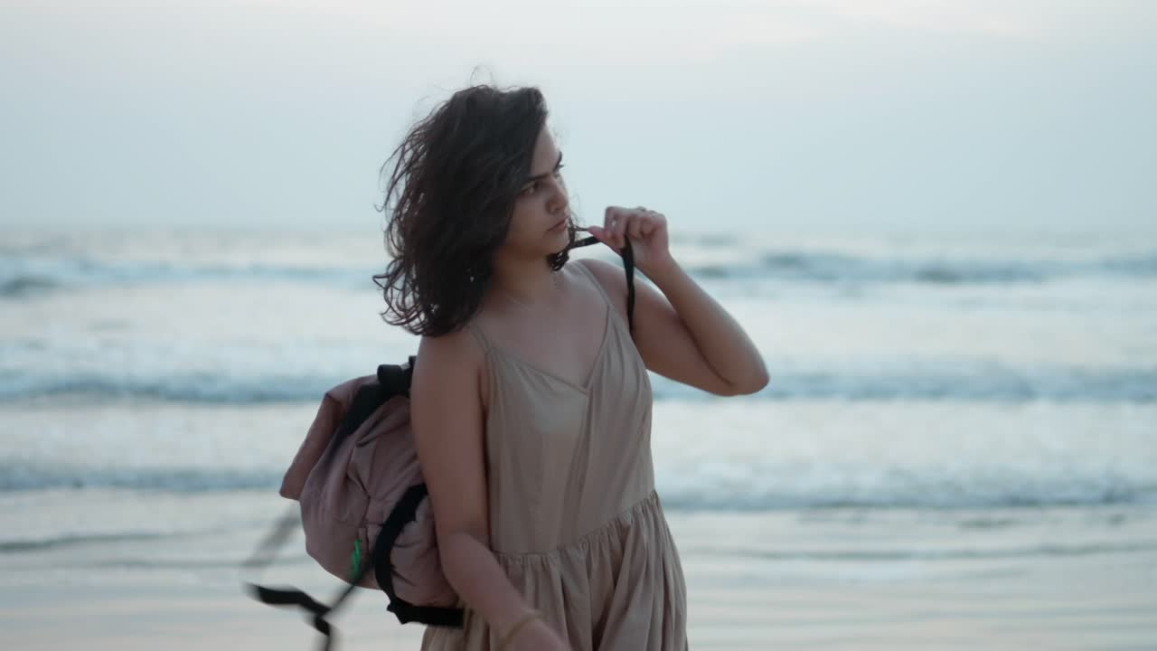 한 여자 가 해변 에서 잠시 즐기면서 장난스럽게 가방 을 흔들고 있다