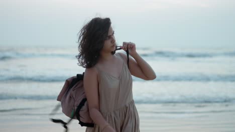 a woman playfully swings her bag while enjoying a moment at the beach