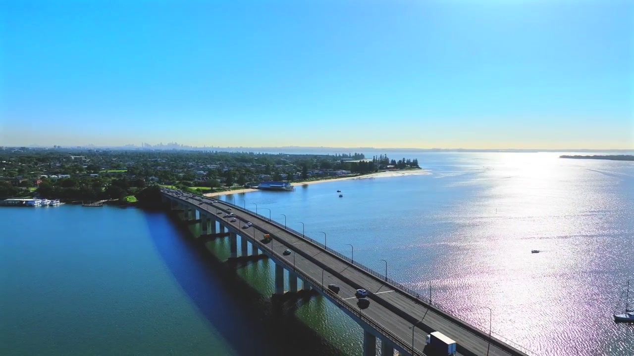 Droneoptagelse, der afslører en konstant strøm af trafik, der kører over en bro mod Sydney, Australien.