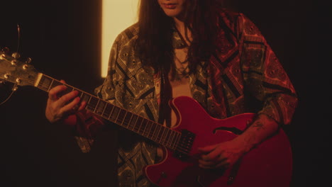 handsome long-haired man playing guitar during performance in studio