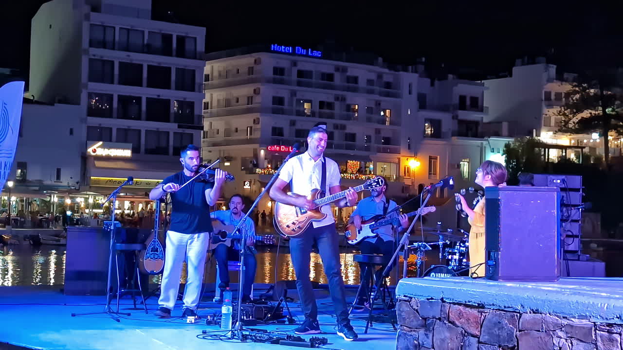 Footage of a local band performing at an event in Agios Nikolaos, Greece during nighttime.