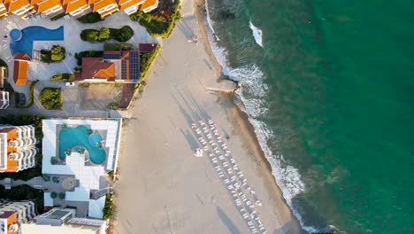 Aerial-view-looking-down-over-sunlit-Robinson-Beach,-Elenite,-Bulgaria-flying-above-holiday-resort-hotel-rooftops