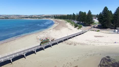 Aerial-shot-of-a-horse-drawn-tram-crossing-the-original-Granite-Island-causeway-into-Victor-Harbor,-South-Australia