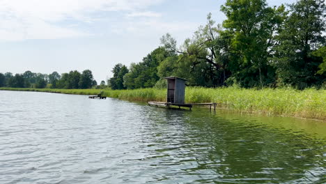 a makeshift wooden house, a shed erected on a small wooden platform near the lake shore