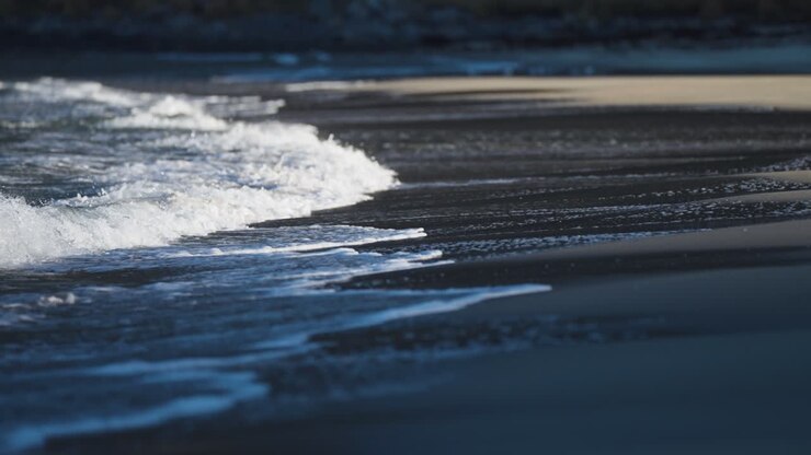 Gentle waves roll slowly on the shallows of the sandy beach in Ersfjord