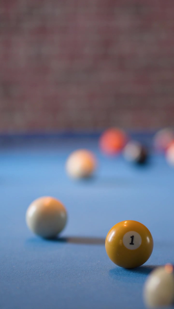Camera slowly advances toward billiards balls on blue table, shallow focus, soft indoor lighting