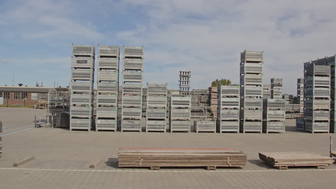 Tilt down from a cloudy sky to stacked materials on an industrial storage yard on a sunny day