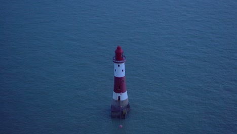 faro blanco y rojo en el mar: luz parpadeante al anochecer