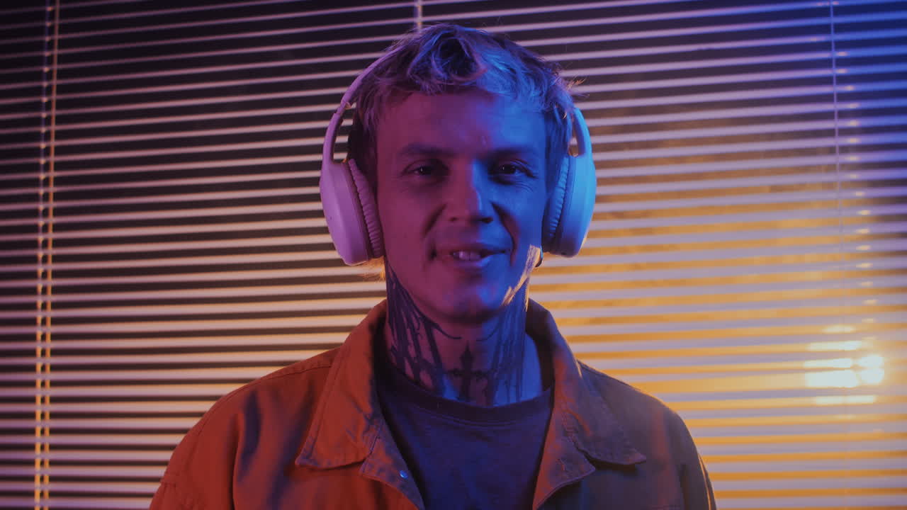 Portrait of Young Musician Enjoying Music in Headphones in Neon Room