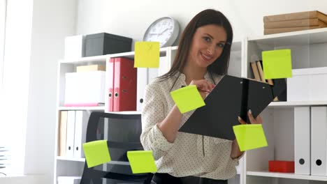 businesswoman making notes in documents standing near glass wall