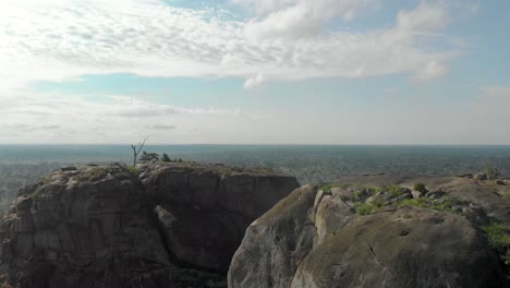 aerial shot flying over the top of a large granite boulder mountain in rural africa