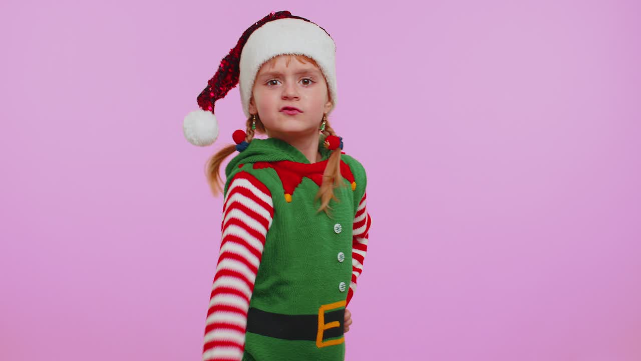 Nespokojená dívka v kostýmu na Vánoce, která rozhazuje rukama v nespokojenosti a obviňuje za neúspěch.