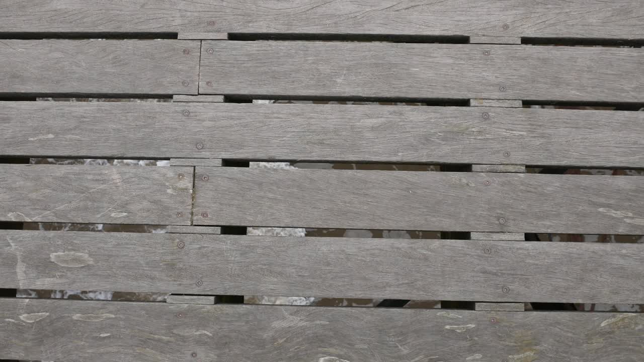 las olas del mar bajo las tablas de madera de la pasarela del muelle en el océano