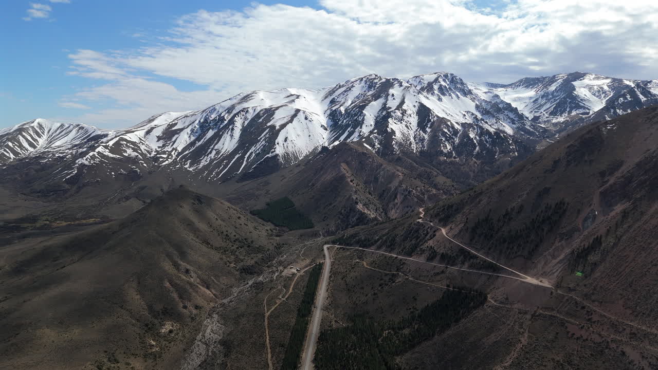 tomada general de avión no tripulado de carretera de tierra y montañas cerca de esquel en el sur argentino, con picos nevados en la parte de atrás. 4k-60fps.