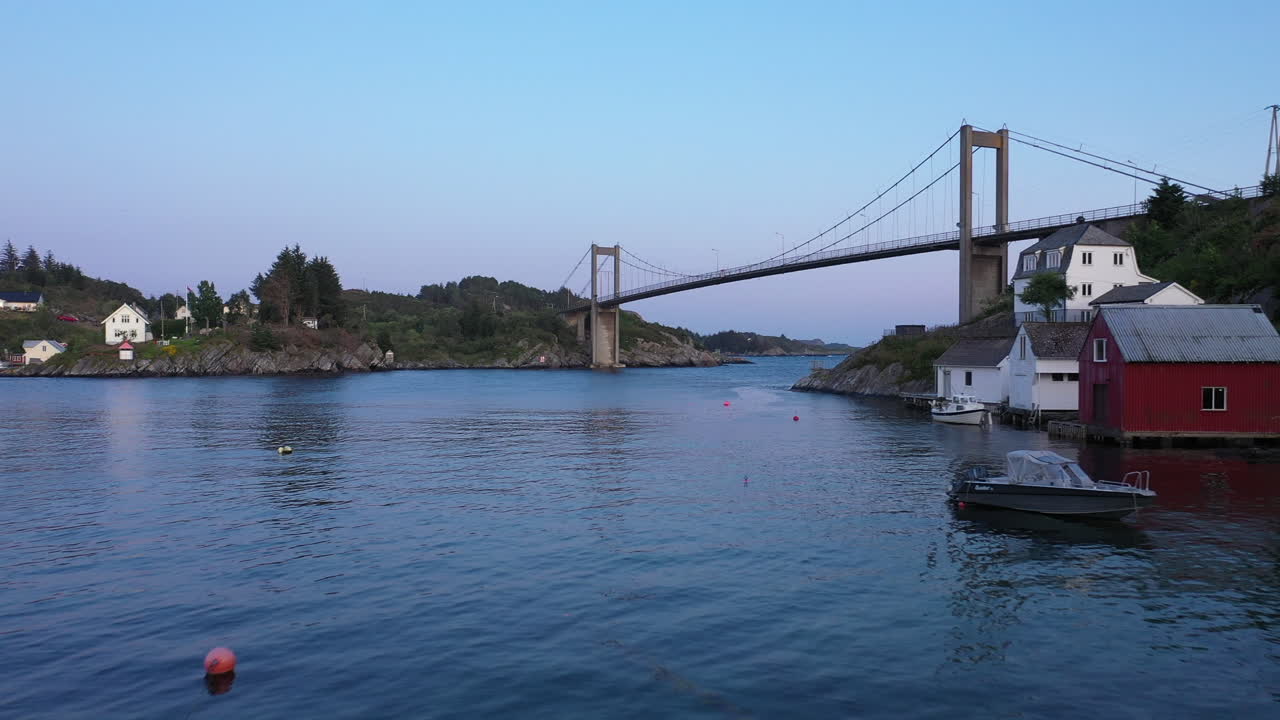 전통적인 보트 하우스와 다리가 있는 아름다운 해안 마을을 드러내는 나무 사이의 드론 샷