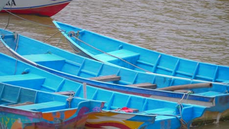 closeup of fishing boats bouncing in rough waters while anchored in harbor, indonesia