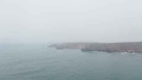 coastal cliffs in serene ocean during hazy morning in portugal