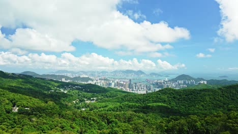 a dynamic ascending aerial footage from below the trees revealing the beautiful cityscape of tseung kwan o new town in hong kong surrounded by skyscrapers, mountains and the beautiful seas