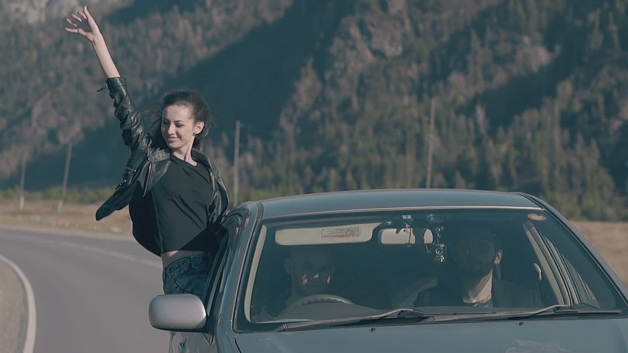 la morena se sienta en la ventana del coche levanta la mano y se siente satisfecha