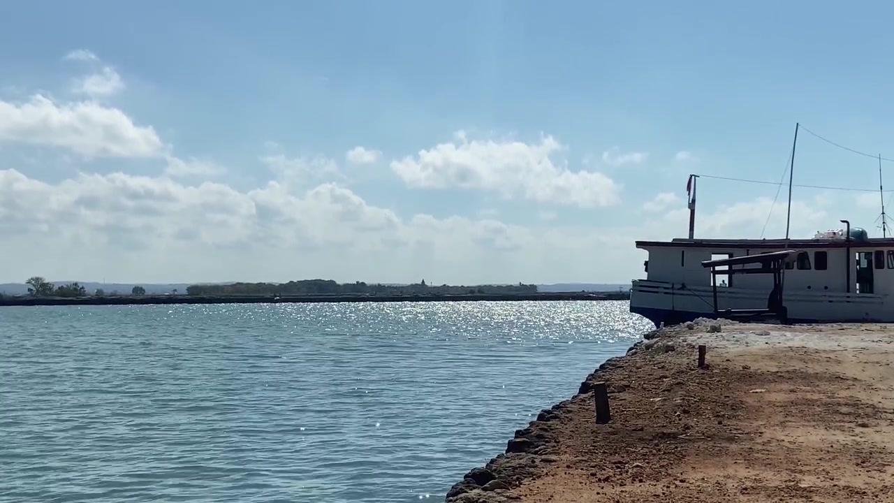 White Boat Docked by Sparkling Blue Water on a Sunny Day