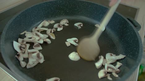champiñones salteados femeninos en una sartén