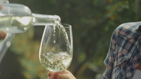 pouring white wine in a garden