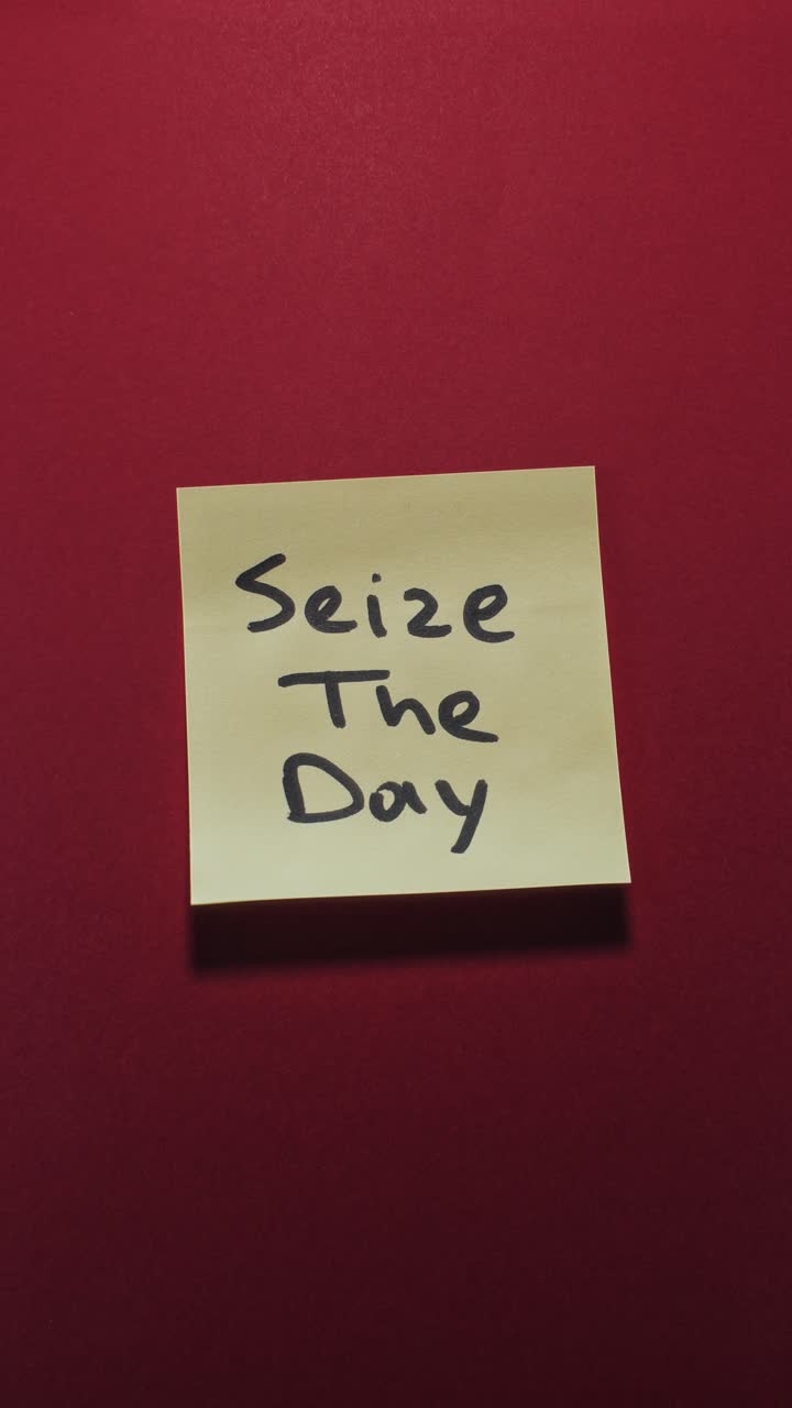 Hands posting Seize The Day sticky note on red wall, highlighting inspiration