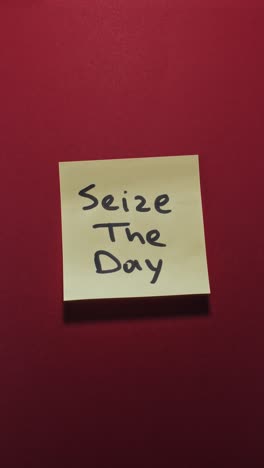 hands posting seize the day sticky note on red wall, highlighting inspiration