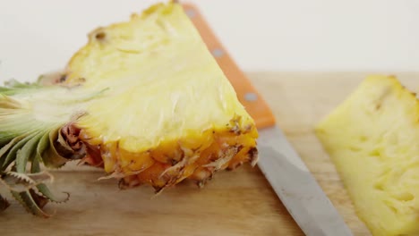 Slices-and-halved-pineapples-on-wooden-table