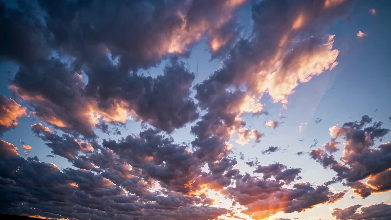 A dramatic wide-angle video captures a vibrant sunset with dynamic clouds, blending warm and cool