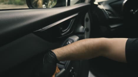 Close-up-of-a-male-wearing-black-gloves-cleaning-a-white-car-with-black-interior-with-a-microfiber-cloth-in-slow-motion