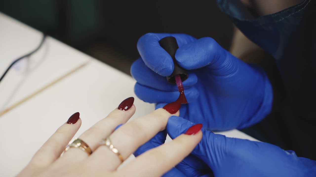 Manicure. Polishing nails with red nail polish in the beauty salon. Hand care in the spa. Close-up