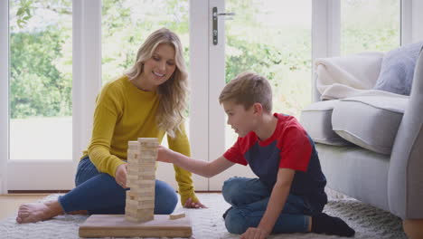 mother and son at home playing game stacking and balancing wooden blocks together