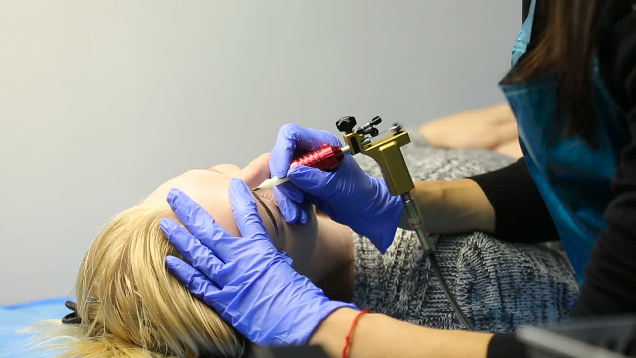 Making eyebrow tattoo. Cosmetician working eyebrow make up at beauty-farm