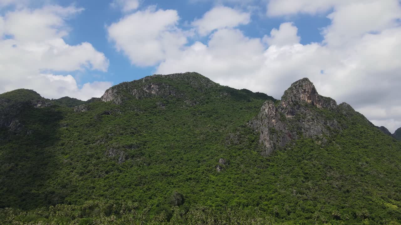 un metraje aéreo deslizándose hacia la derecha de esta hermosa montaña de piedra caliza con pesadas nubes blancas y cielo azul, parque nacional sam roi yot, prachuap khiri khan, tailandia