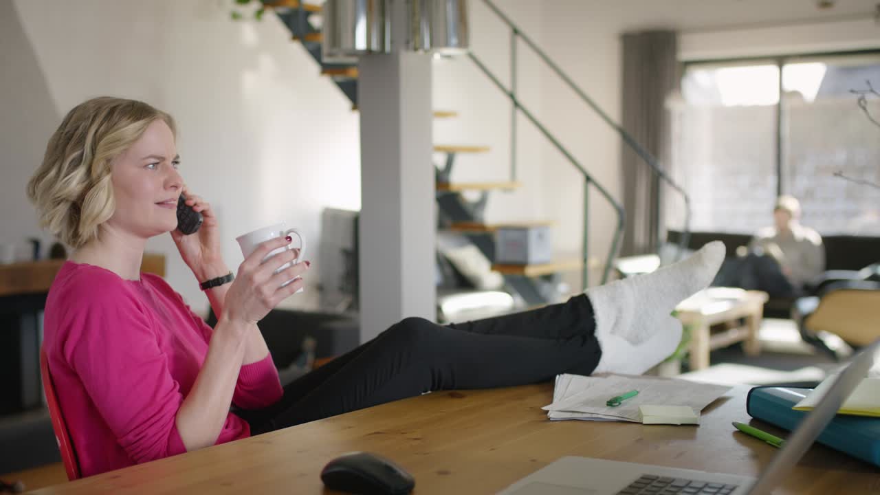 Handsome Woman at home, with Feet on Table speaking on Mobile Phone